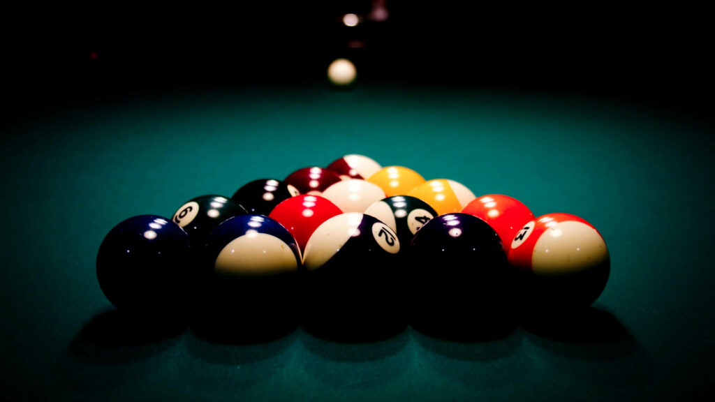 Close up of billiards balls racked on green pool table with dramatic shadows and focused lighting Wallpaper