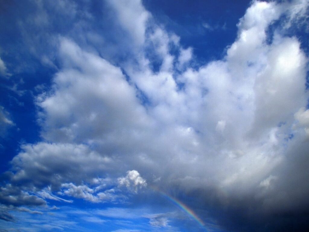 Dramatic clouds and faint rainbow over Utah national park landscape under vivid blue sky wallpaper