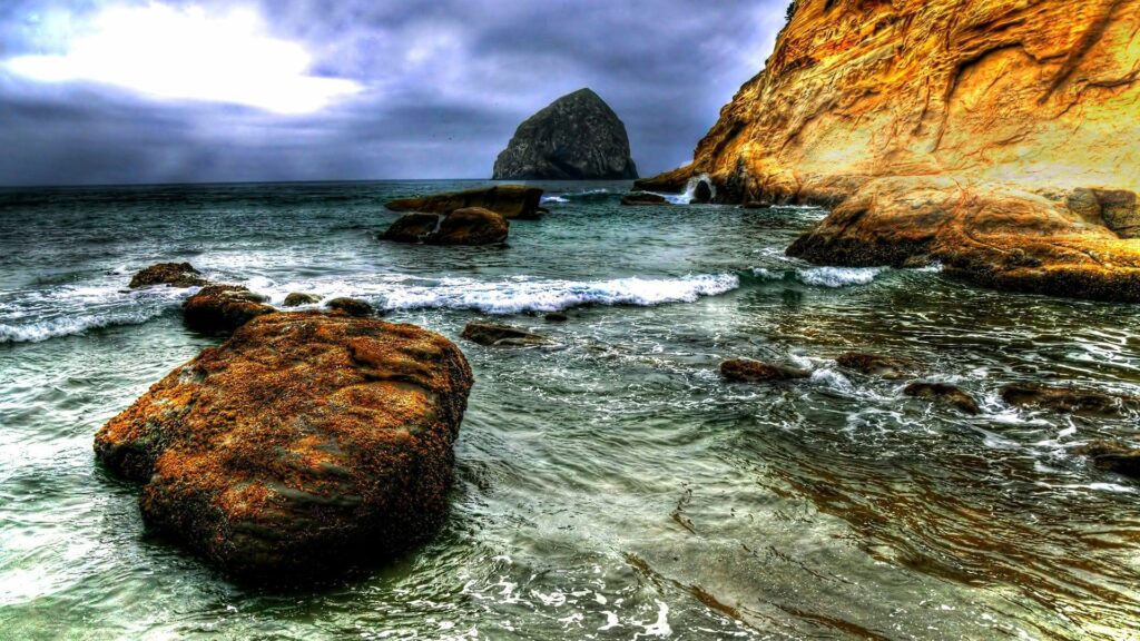 Dramatic coastal wallpaper with rugged cliffs boulders and foamy waves under overcast sky