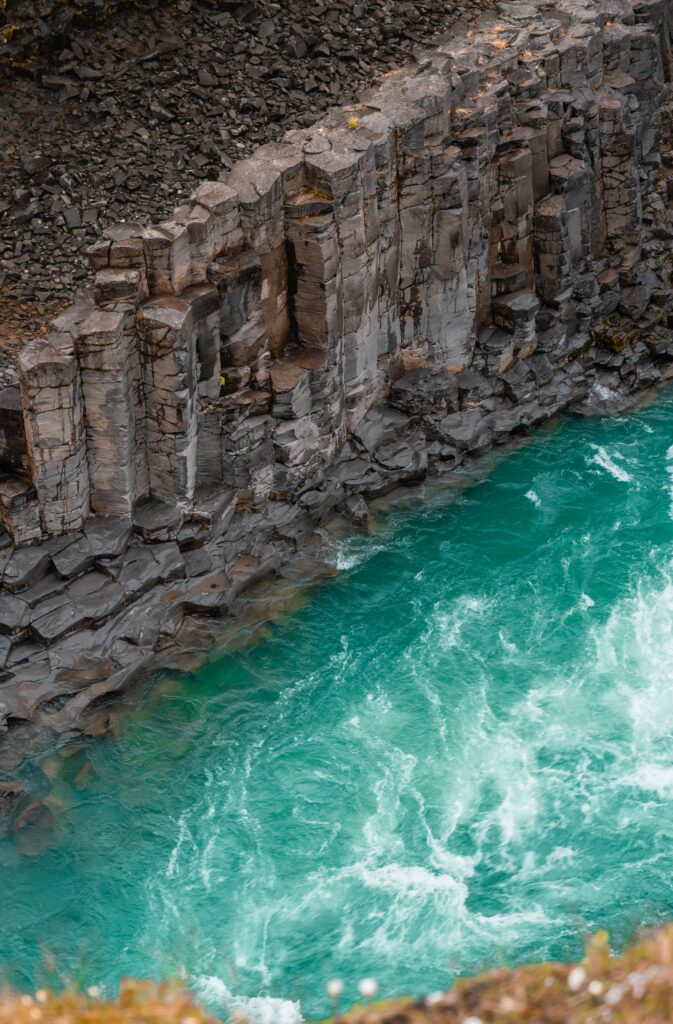 Dramatic coastal wallpaper with rugged stone cliffs meeting vibrant turquoise sea surf waves