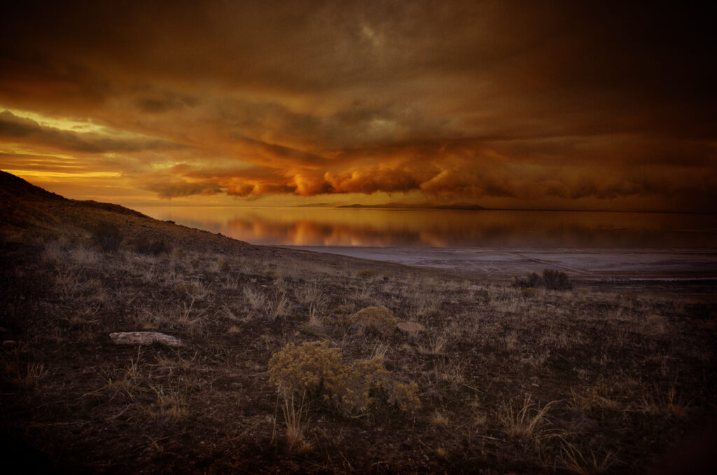Dramatic coastal dusk wallpaper with fiery clouds reflecting on calm water and rugged terrain