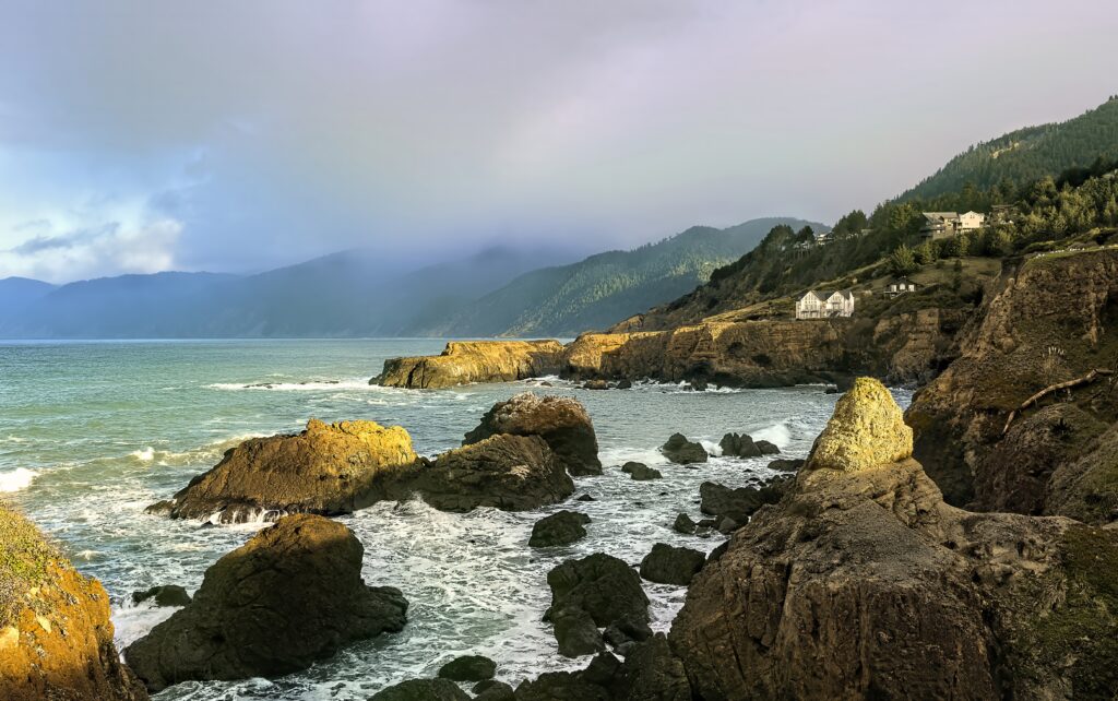 Dramatic coastal landscape with rugged stone formations lush green hills and soft fog wallpaper
