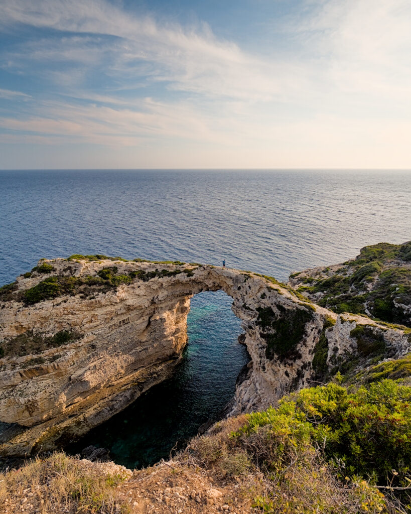 Dramatic natural rock arch above deep blue sea with cliffs and lush greenery coastal wallpaper