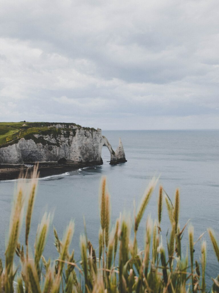 Dramatic coastal landscape with rugged rocks natural stone arch calm sea and overcast skies wallpaper