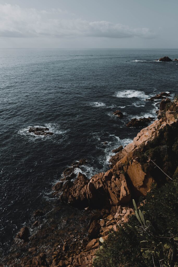 Dramatic coastal wallpaper with rugged rocks crashing waves cloudy sky serene seaside view