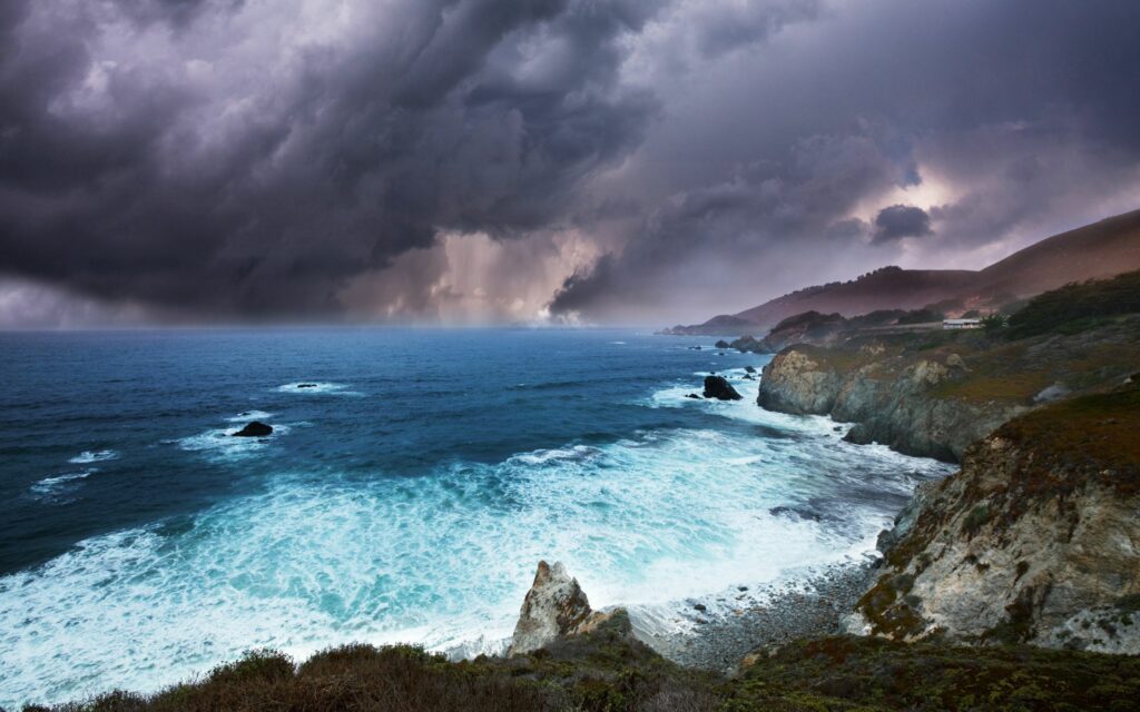 Dramatic coastal wallpaper with crashing waves rugged rocks swirling sea foam stormy sky background