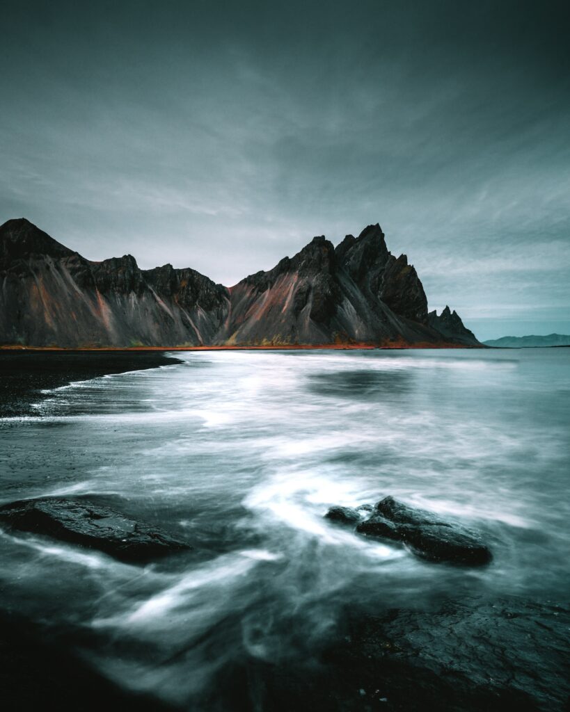 Dramatic coastal wallpaper with rugged mountains steep cliffs misty beach and moody overcast sky