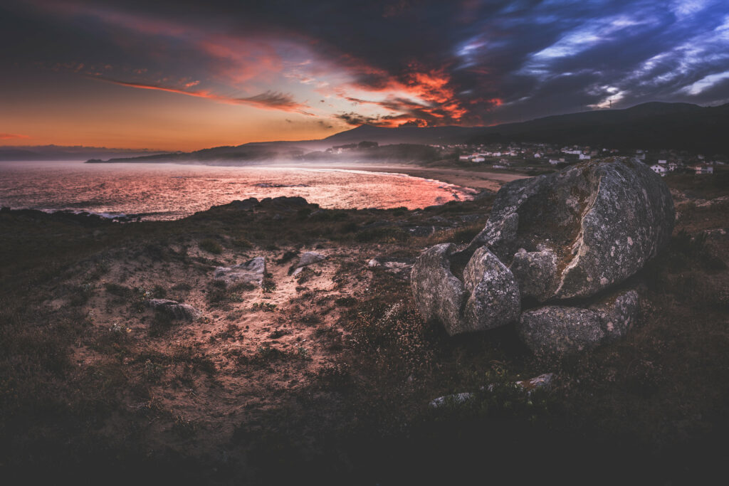 Dramatic dusk coastline wallpaper with rugged stones fiery sunset dark waves and moody sky