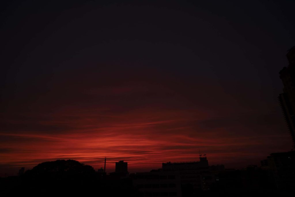 Dramatic crimson sunset sky over dark silhouetted city skyline vibrant moody wallpaper background