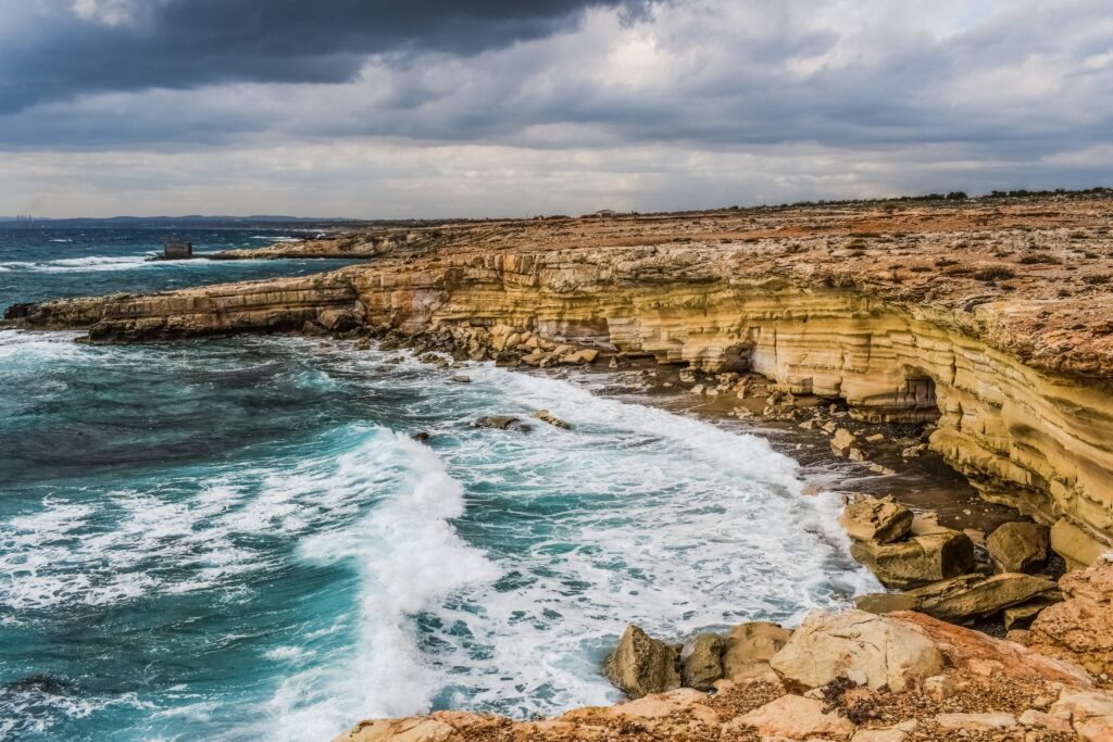 Rugged Cyprus cliffs with crashing Mediterranean waves under moody overcast sky wallpaper