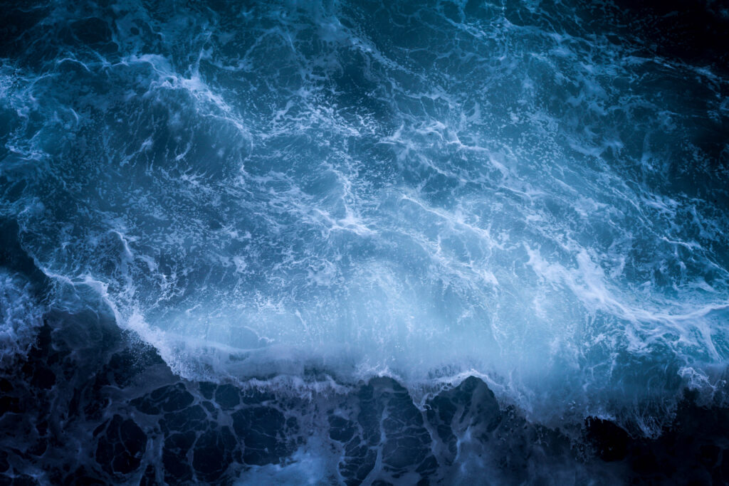 Dramatic sea wallpaper with powerful deep blue waves swirling surf and foamy water texture