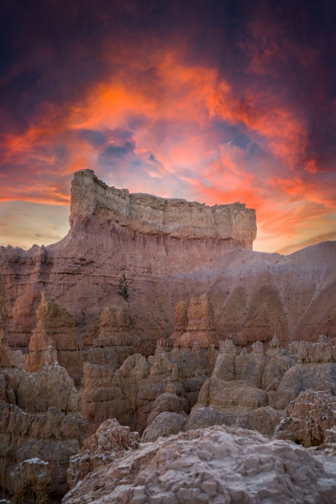 Dramatic dusk mountain landscape with towering cliffs rugged rocks and vibrant orange purple sky Wallpaper