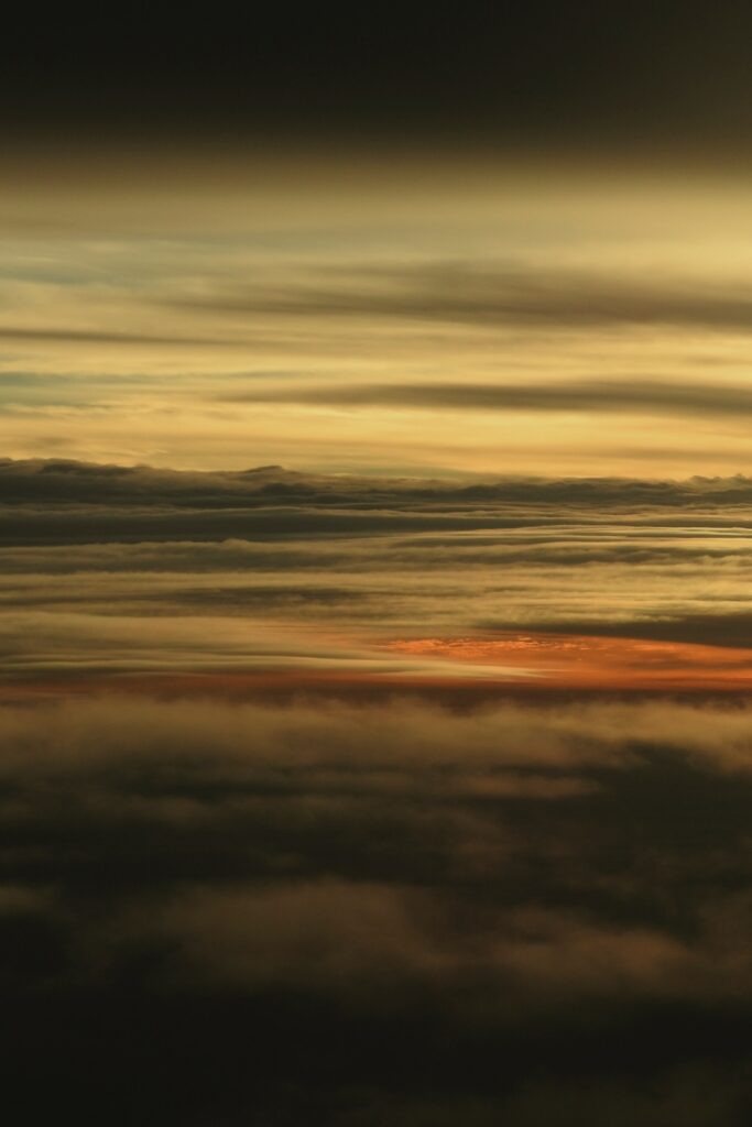 Dramatic dusk sky with dark and golden clouds illuminated by warm setting sun wallpaper background