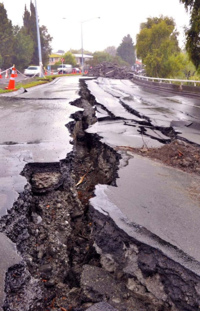 City road cracked by earthquake with broken asphalt debris under overcast somber sky wallpaper