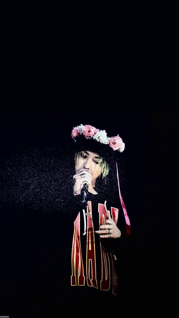 G-Dragon singing in floral crown dramatic high contrast black background K-pop wallpaper