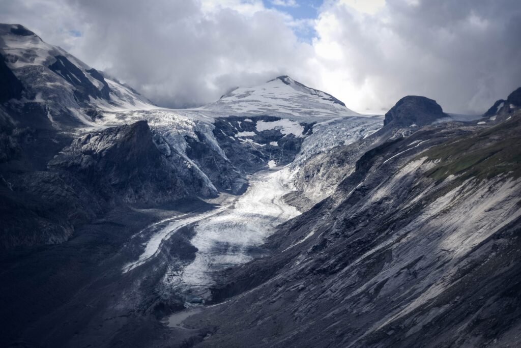 Dramatic glacier winding through foggy rugged mountains with icy textures and moody tones Wallpaper