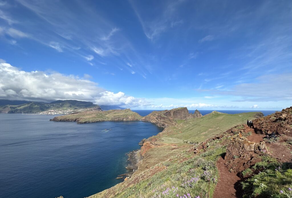 Dramatic green hills and mountains meet deep blue sea under vast cloudy sky coastal wallpaper background