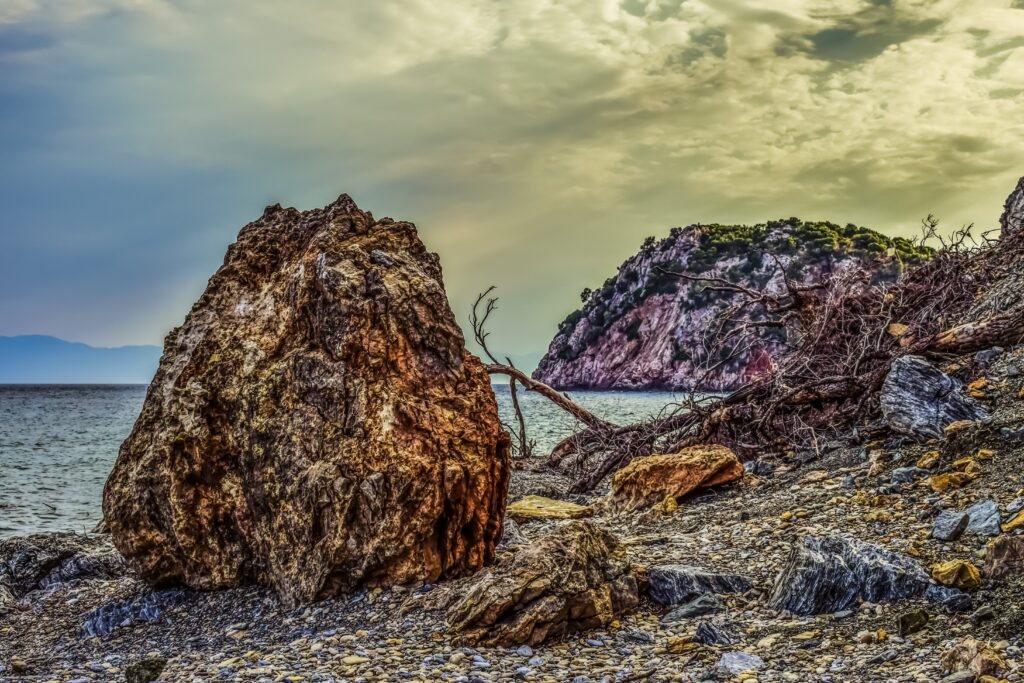 Dramatic beach wallpaper with vivid HDR pebbles boulder coastal cliffs and colorful moody sky