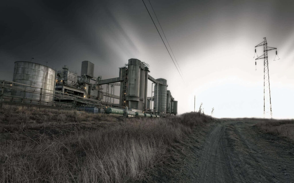 Sprawling industrial factory with metallic structures under dramatic overcast sky wallpaper background