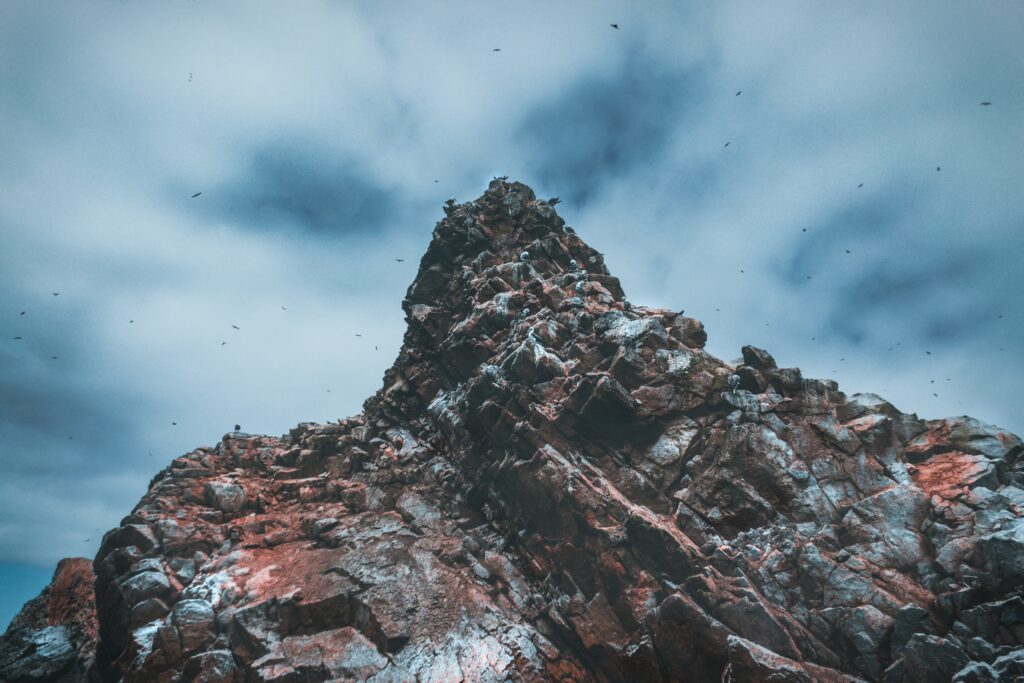 Dramatic Islas Ballestas cliffs with jagged rocks seabirds and cloudy sky coastal landscape wallpaper