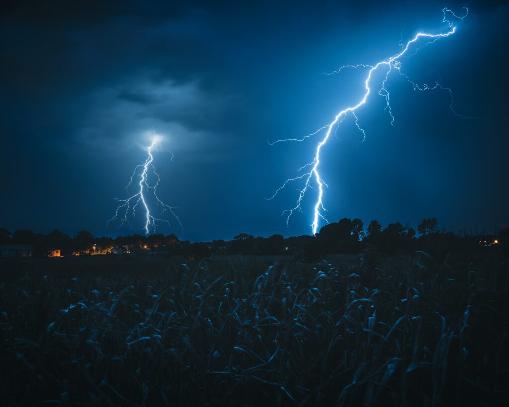 Dramatic night sky with vivid lightning bolts over dark silhouetted landscape wallpaper background