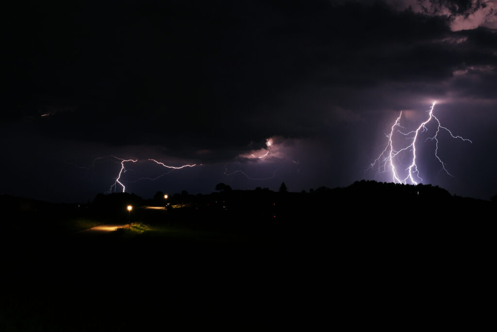 Vivid lightning bolts illuminate dark night sky striking landscape in dramatic cinematic scene wallpaper