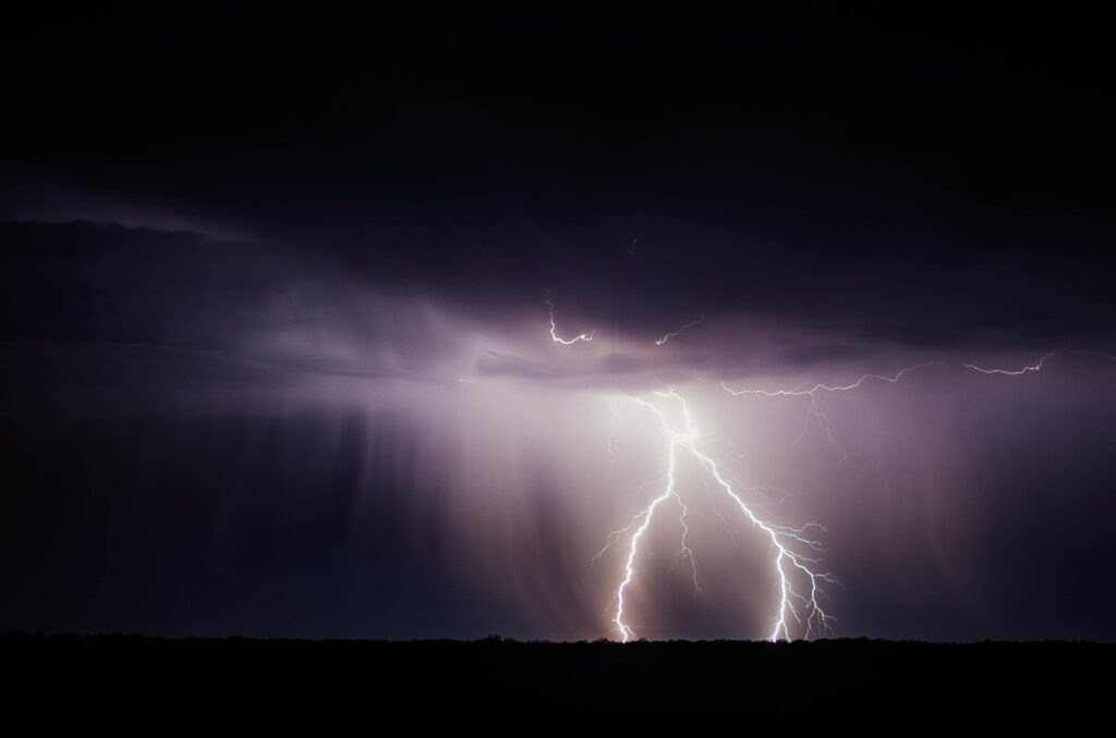 Dramatic lightning strike over dark stormy sky with dense clouds and heavy rain wallpaper background