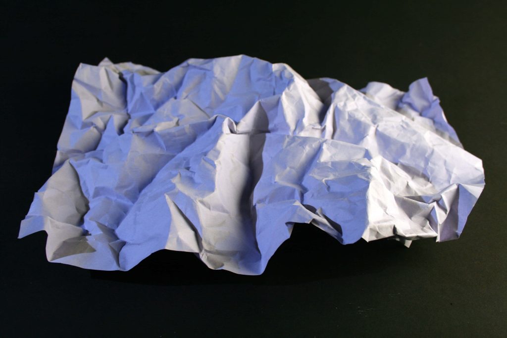 High-contrast crumpled white paper wallpaper with dramatic shadows and cool-toned highlights