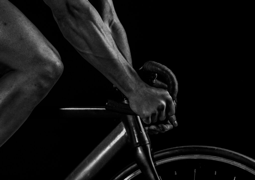Monochrome close-up of cyclist gripping handlebars showing muscular arms and sleek bike design Wallpaper