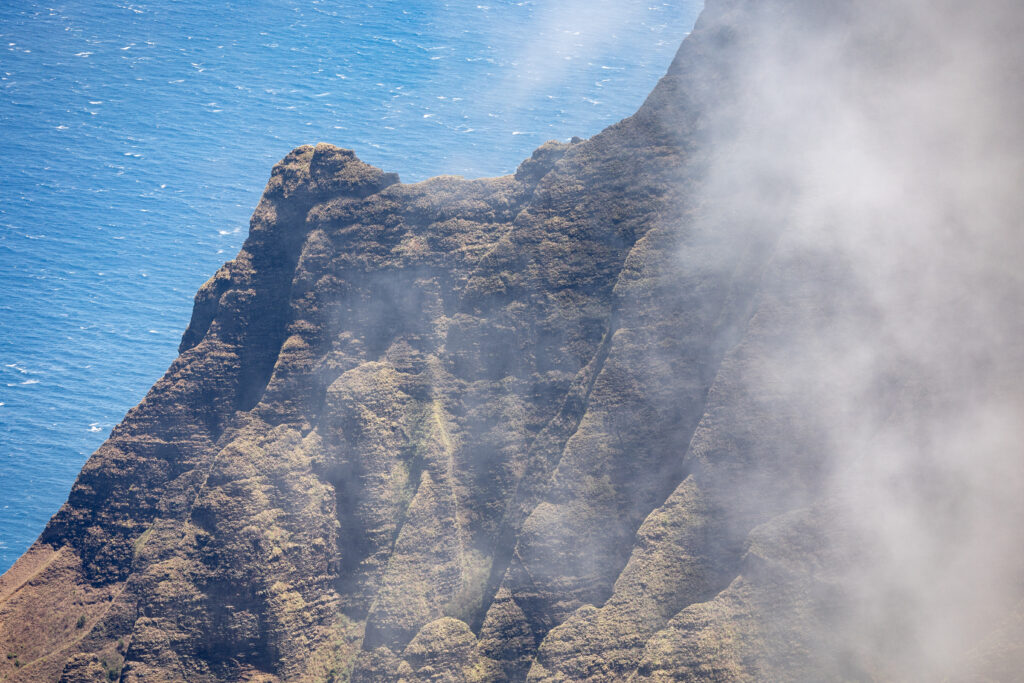 Dramatic mountain cliffs with misty clouds overlooking vibrant blue sea natural landscape wallpaper