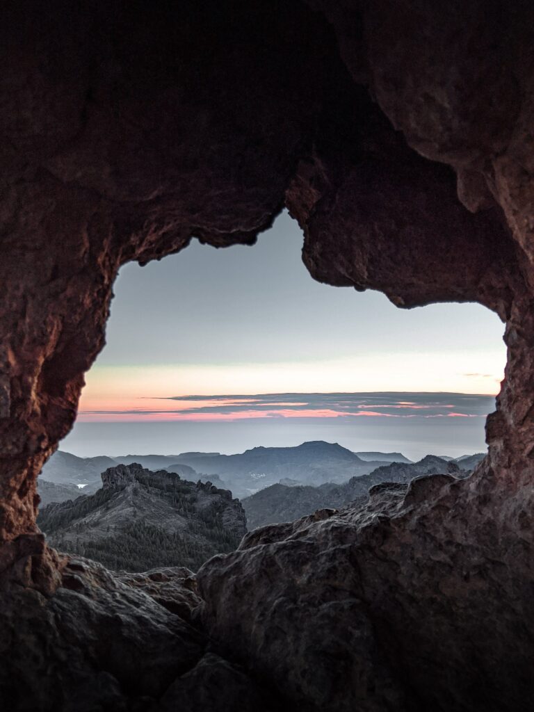 Rugged rocks frame a serene mountain landscape at dawn with layered horizons and rocky textures Wallpaper