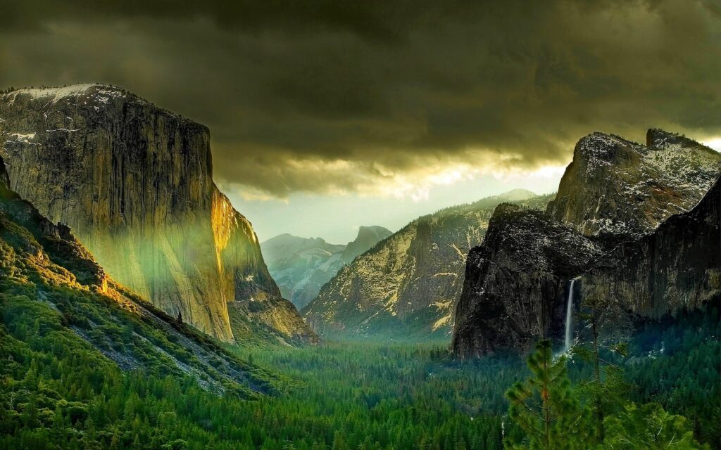 Dramatic mountain landscape with rugged rocks golden sunlight and dense coniferous forest valley Wallpaper