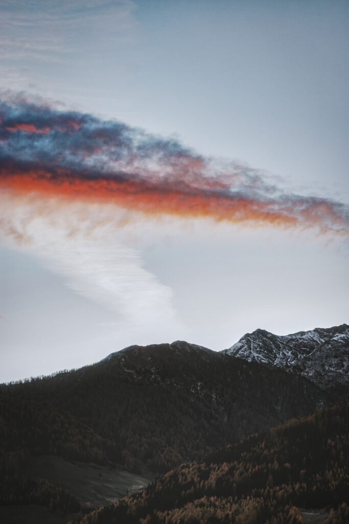 Dramatic mountain peak with colorful autumn trees and vivid red blue clouds in evening sky Wallpaper