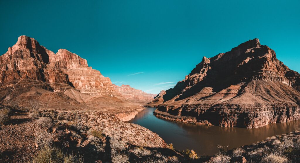 Dramatic mountain landscape with cliffs valley winding river and serene lake under blue sky wallpaper