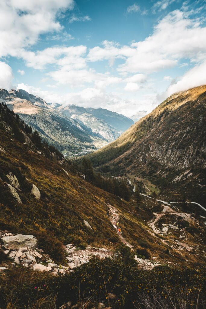 Dramatic mountain landscape with rocky slopes winding path lush green valley and majestic peaks Wallpaper