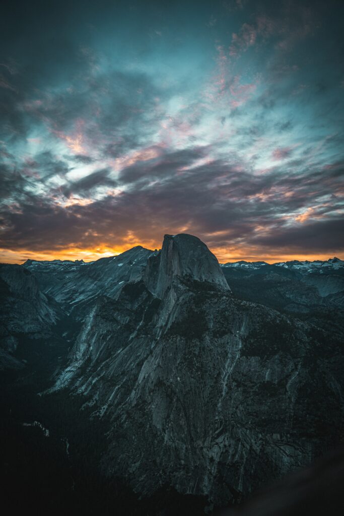 Dramatic mountain peak at sunset with swirling clouds rugged blue landscape wilderness wallpaper