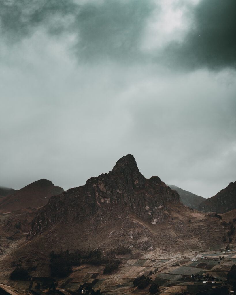 Dramatic mountain peak with moody sky and rugged earth tones perfect for nature wallpaper