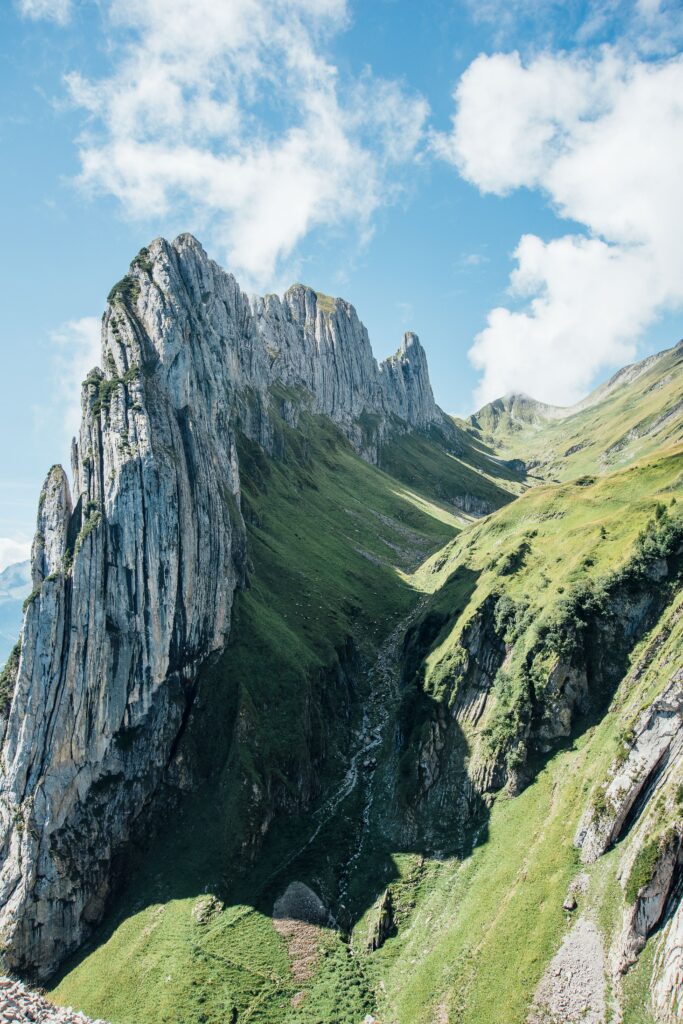 Dramatic mountain wallpaper with sharp rocky peaks lush green slopes and narrow gorge background