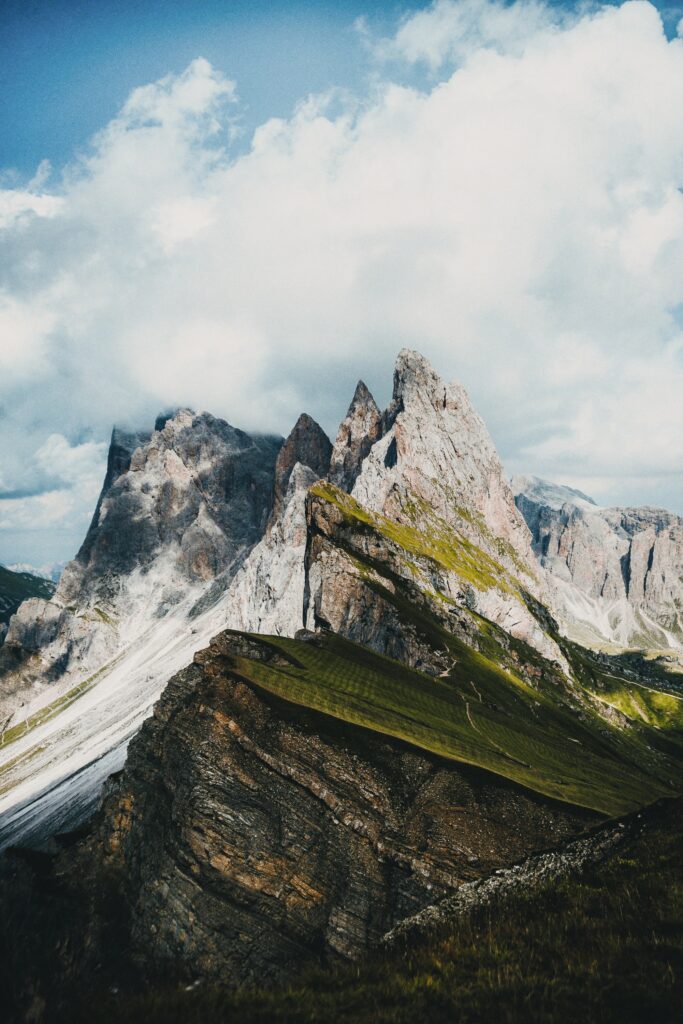 Dramatic mountain peaks above green slopes under vibrant cloudy sky nature wallpaper background