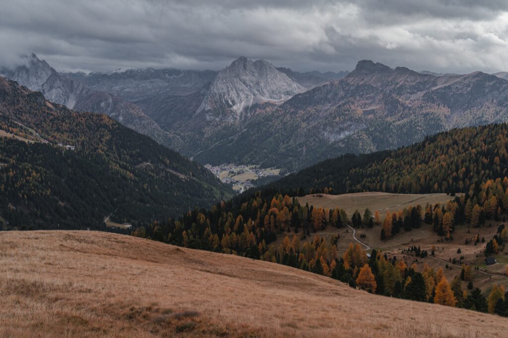 Dramatic mountain range with rugged peaks autumn forest and tranquil valley under moody sky wallpaper