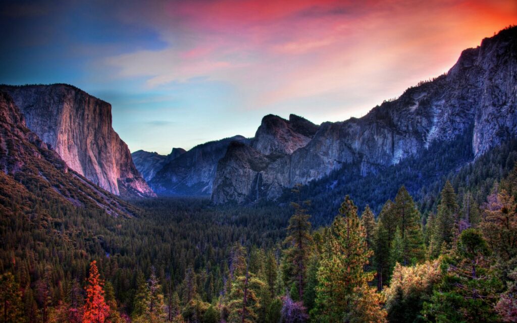 Sunset wallpaper with vivid pink purple blue sky over dramatic mountain ridges and lush forest