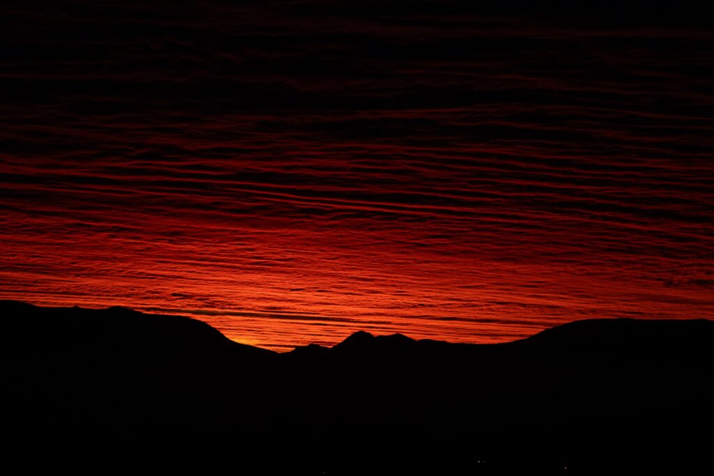 Silhouette of mountain peaks with vibrant red and orange sunset sky wallpaper background