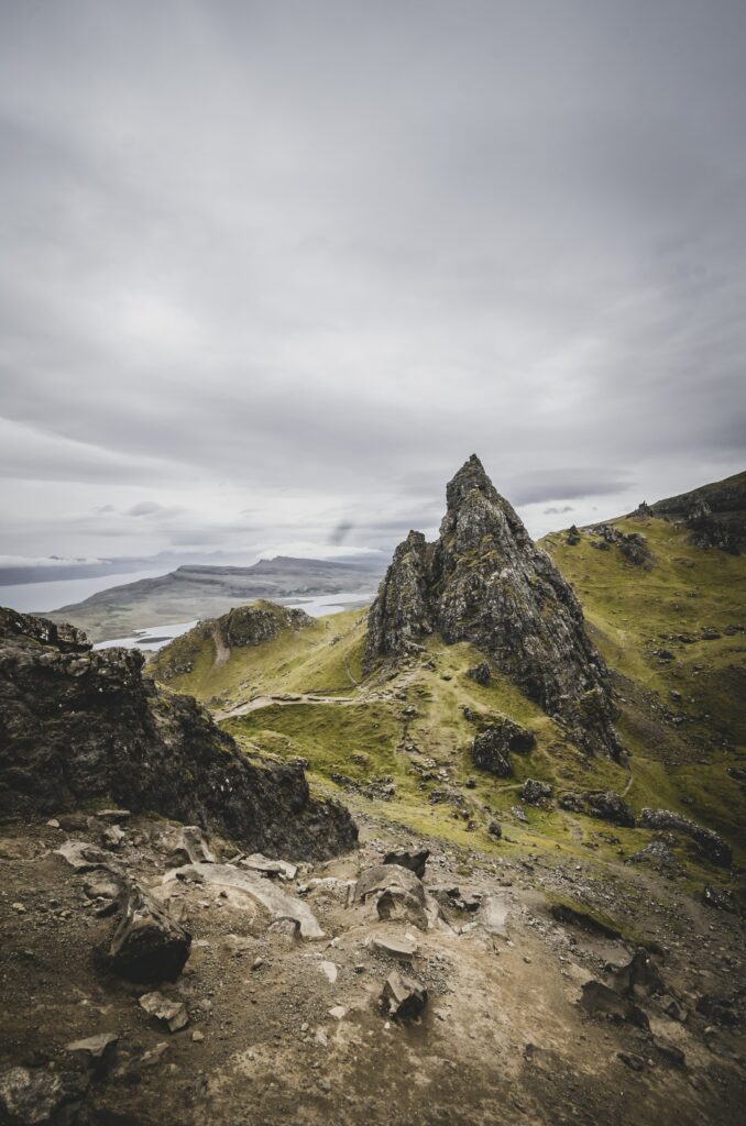 Rugged rocky mountains with green slopes under moody overcast sky natural landscape wallpaper