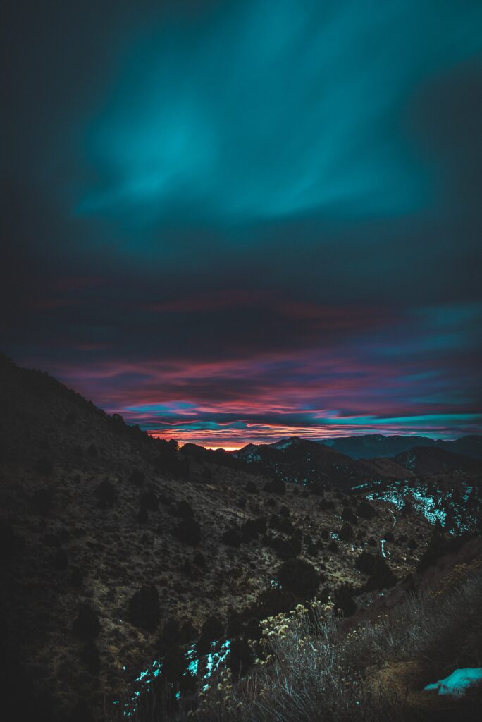 Dramatic mountain landscape at twilight with vivid orange pink sunset fading into deep blue sky Wallpaper