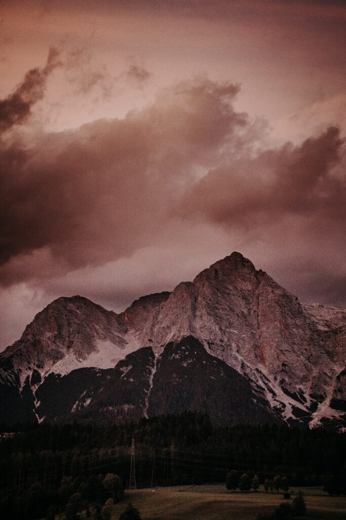 Dramatic mountain wallpaper with rugged peaks and moody clouds in warm dusky tones