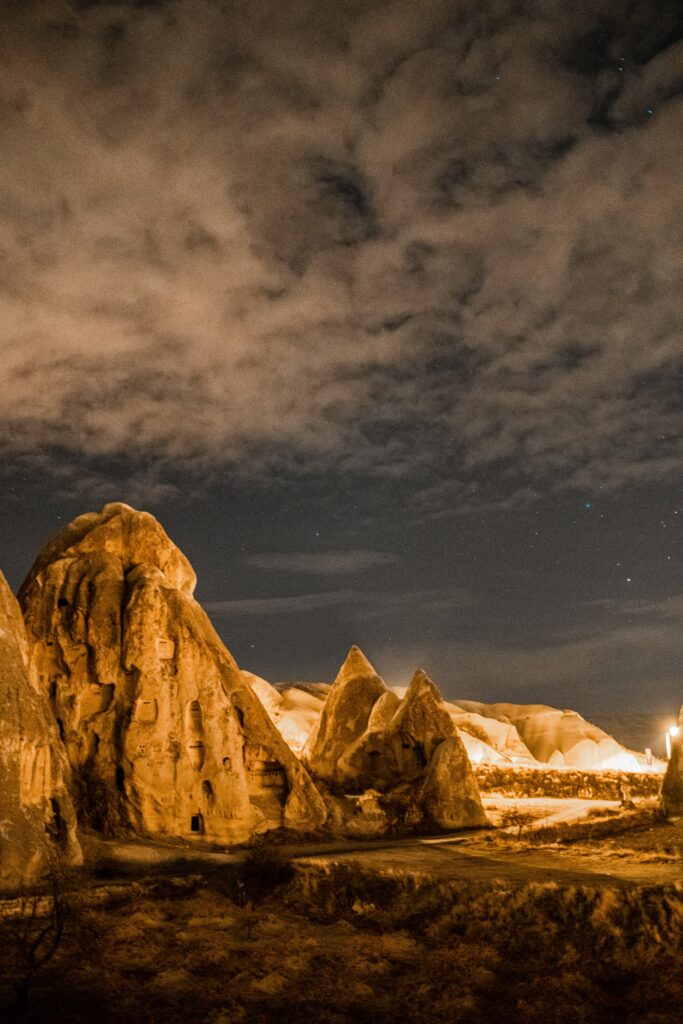 Rugged rocks glowing warm under a dark cloudy night sky dramatic natural landscape wallpaper