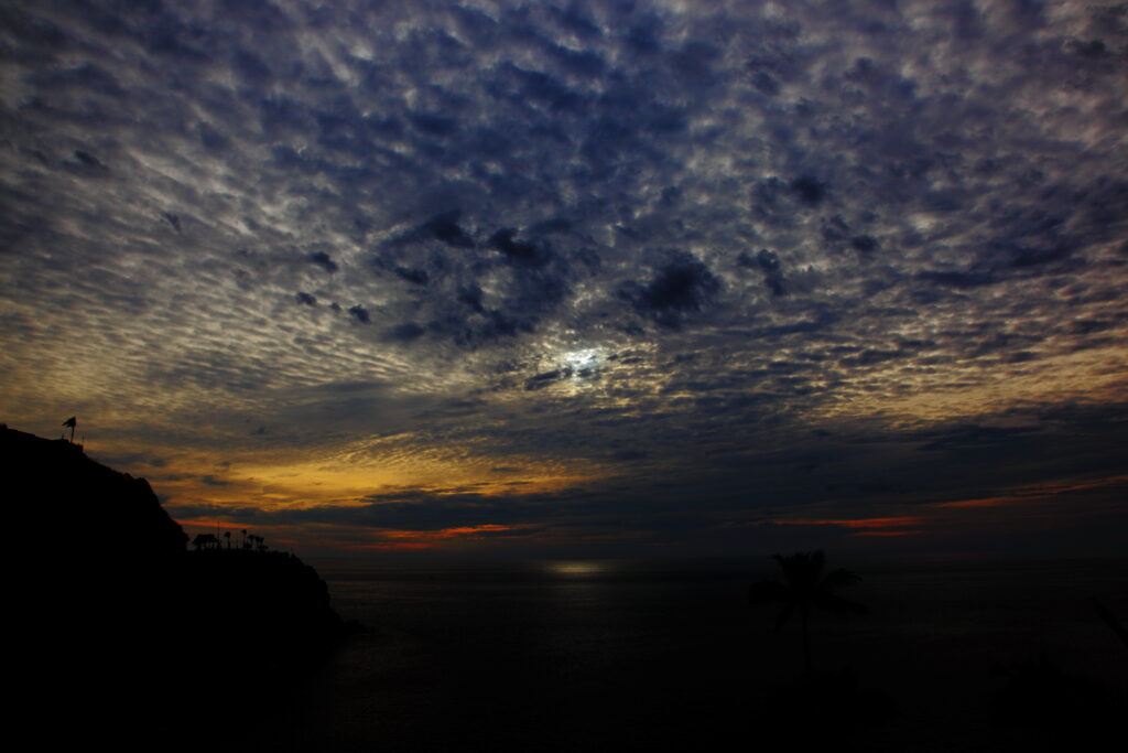 Nightfall seascape wallpaper with dark clouds sunset sky reflected on calm sea and silhouetted cliffs