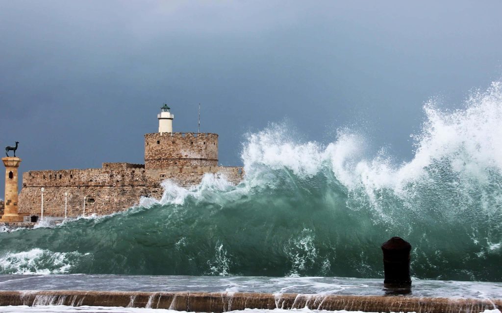 Massive ocean wave crashes on Fort of St Nicholas Rhodes stormy sky ancient stone fortress lighthouse Wallpaper