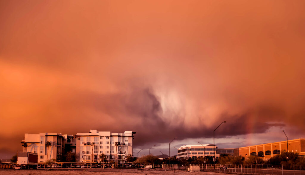Orange dust storm approaches modern cityscape with white glass buildings dramatic sky background Wallpaper