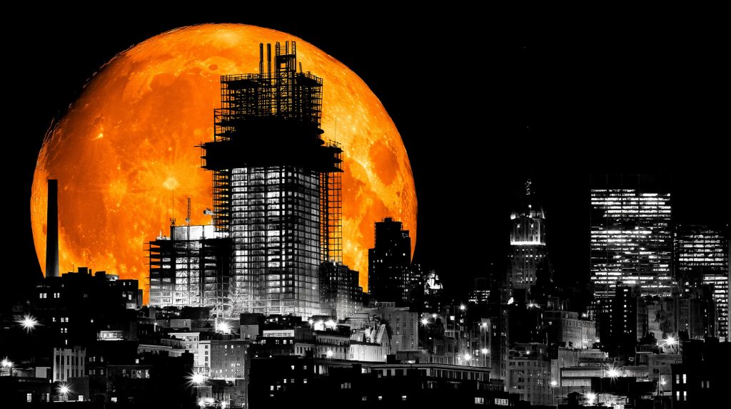 Dramatic orange moon over monochrome city skyline with skeletal high-rise under construction Wallpaper